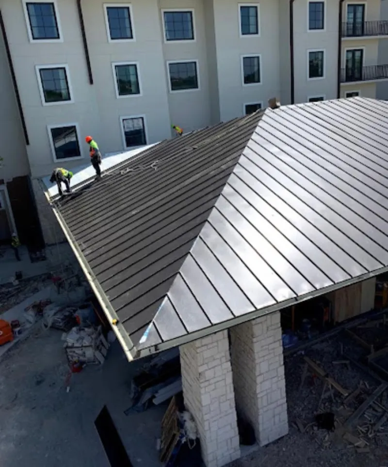 Crew installing standing seam metal roof panels on a commercial project in Dingman